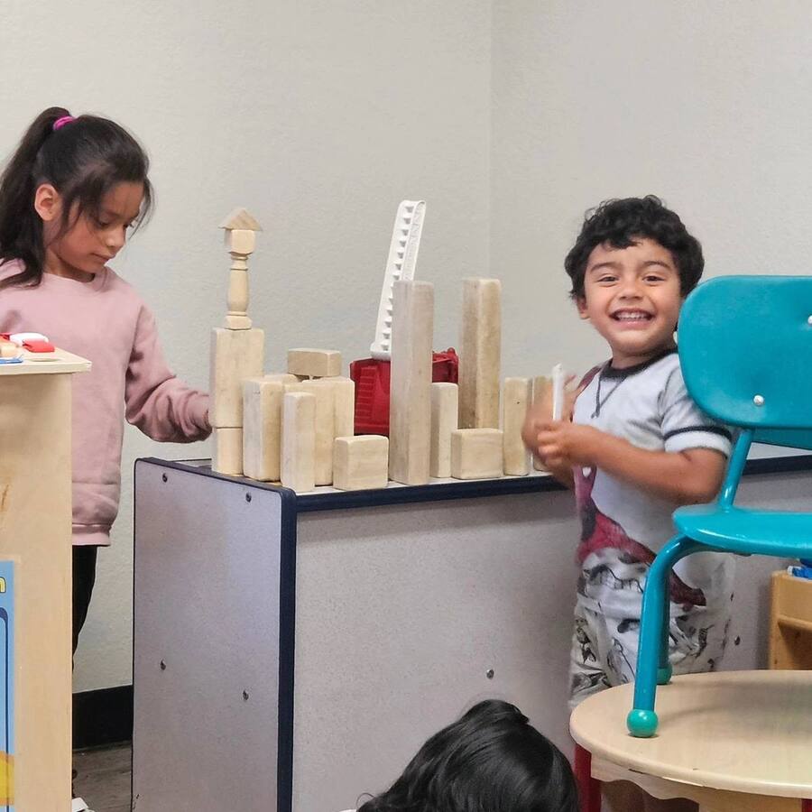 Two children building a tower of wooden blocks