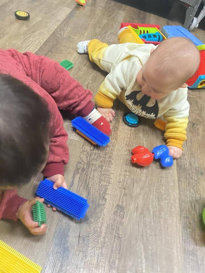 Babies exploring sensory toys on the floor